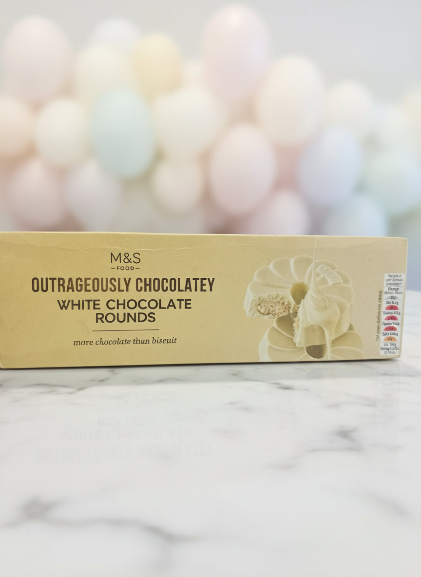 Box of M&S Outrageously Chocolatey White Chocolate Rounds held by a person.
